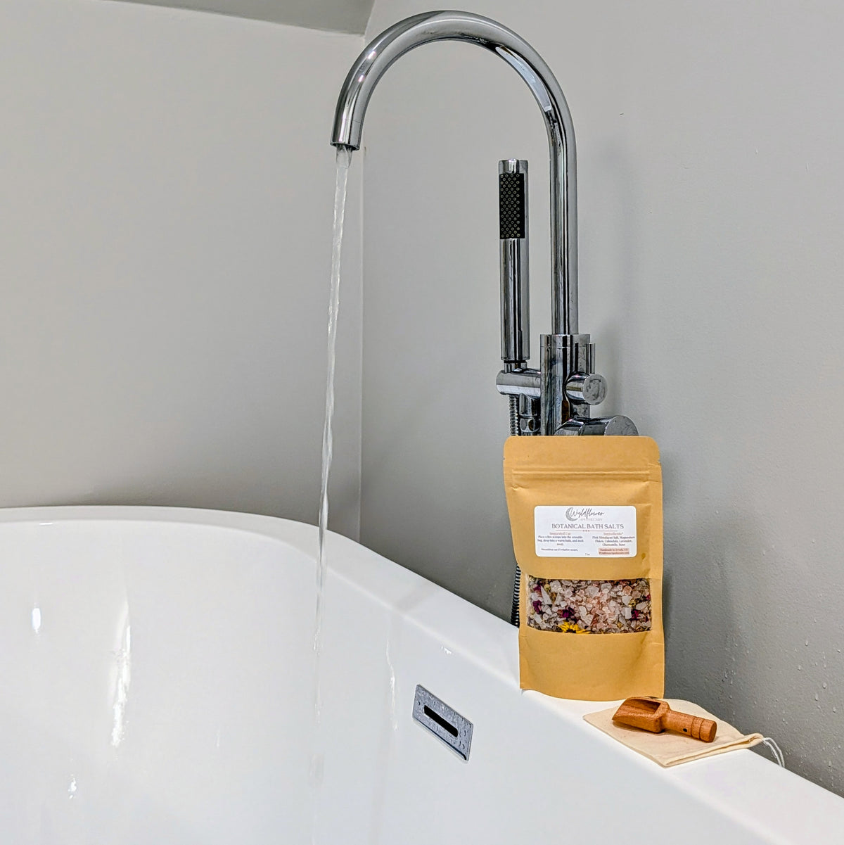 Wyldflower Apothecary Botanical Bath Soak beside a running bath