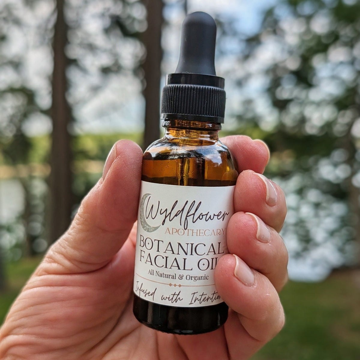 Hand holding a bottle of Wyldflower Apothecary organic facial oil outdoors in Colorado